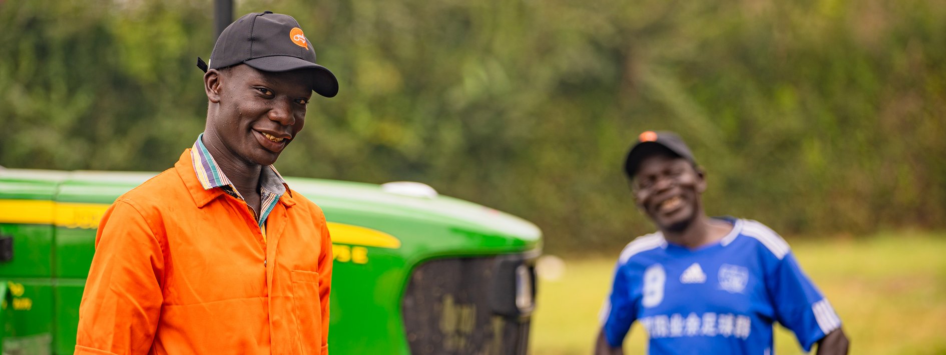 Hello Tractor: Two farm workers standing in front of a tractor
